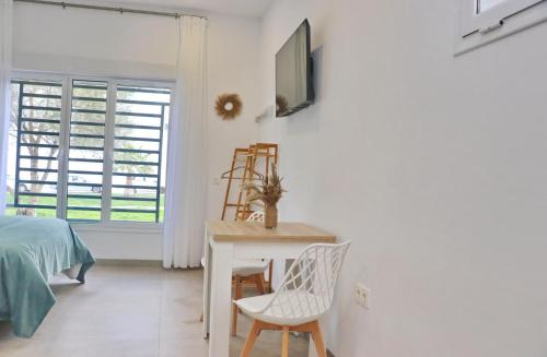 - une chambre avec un lit, un bureau et une télévision dans l'établissement La Ilusión, à Conil de la Frontera