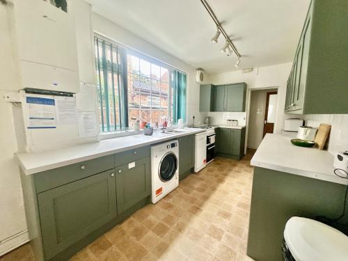 a kitchen with green cabinets and a washer and dryer at Nunmill Nest By Bishy Road With Free Parking in York