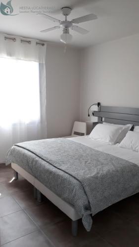 a bedroom with a large bed with a ceiling fan at Calme et Central à Jonzac in Jonzac