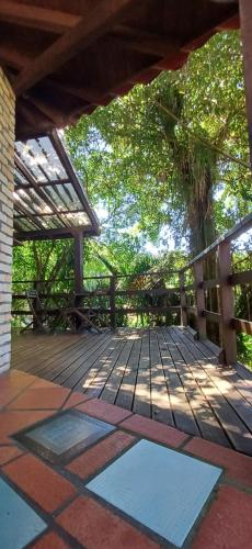 un porche con una terraza de madera con árboles en el fondo en Casa próxima à lagoa, en Florianópolis