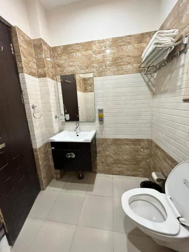 a bathroom with a toilet and a sink and a mirror at Hotel Landmark in Sahāranpur