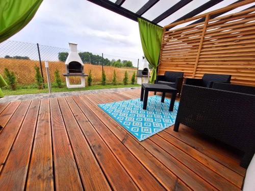 a wooden deck with two chairs and a grill at Siedem mórz in Gąski