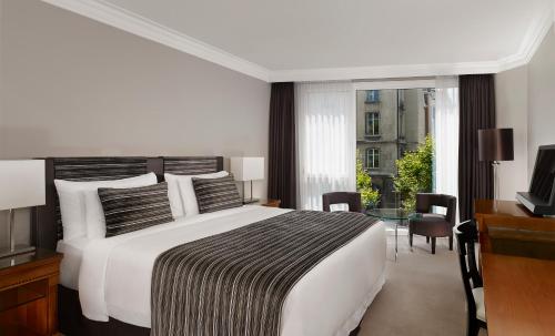 a bedroom with a bed and a desk and a television at Hotel President Wilson, a Luxury Collection Hotel, Geneva in Geneva