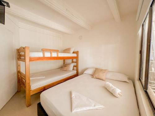 two bunk beds in a small room with a window at Hotel Tamara House in Santa Marta