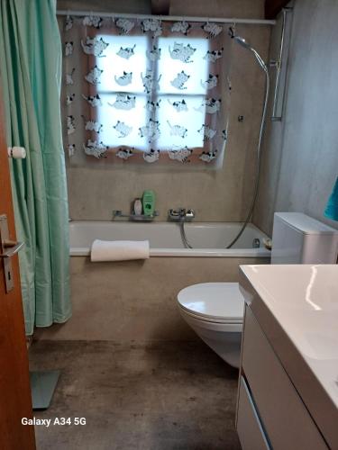 a bathroom with a tub and a toilet and a window at Afrika Zimmer mit Bergblick in Emmetten