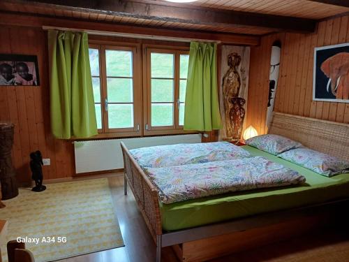 a bedroom with a bed with green curtains and a window at Afrika Zimmer mit Bergblick in Emmetten