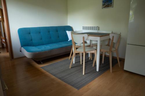 - un salon avec un canapé bleu, une table et des chaises dans l'établissement Słoneczne Wzgórze DOMEK, à Szczawnica
