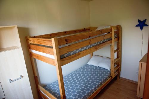 Ce lit superposé se trouve dans un dortoir doté d'un couvre-lit bleu. dans l'établissement Słoneczne Wzgórze DOMEK, à Szczawnica