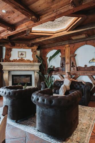 a man sitting on a couch in a living room with a fireplace at Hotel Querceto Wellness & Spa - Garda Lake Collection in Malcesine