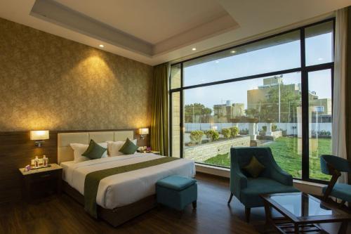 a hotel room with a bed and a large window at Sarovar Portico, Somnath in Somnath