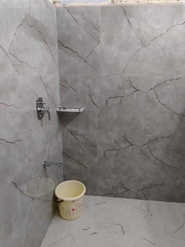 a bathroom with a toilet and a marble wall at Zingle Stay Airport Hotel in Chennai