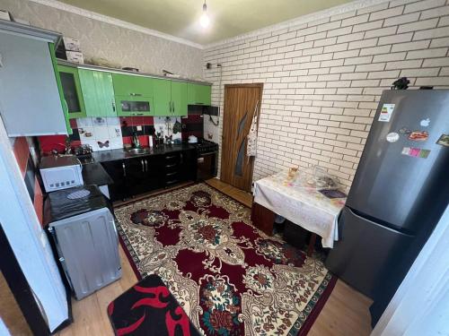 eine Küche mit einem Kühlschrank und einem Tisch darin in der Unterkunft Green West House in Bischkek