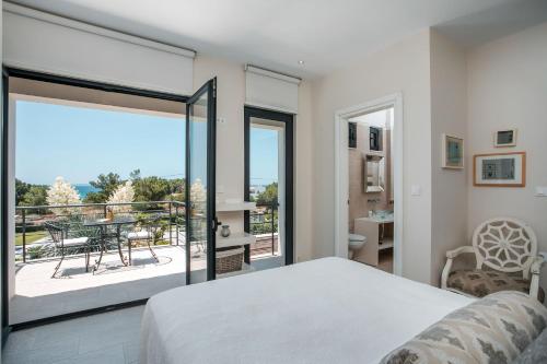 1 dormitorio con 1 cama y balcón con mesa en Oneiro Villa - Voted the best Villa in Rhodes, Greece!, en Pefki