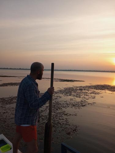 a man holding a wooden pole on the beach at Windy Villa in Polonnaruwa