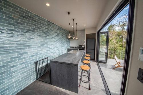 a kitchen with a counter and a blue brick wall at Doggo伊豆　愛犬と過ごす最高の時間の為に造られた貸切宿。温泉、プライベートドッグランで最高の一時を。 in Ito
