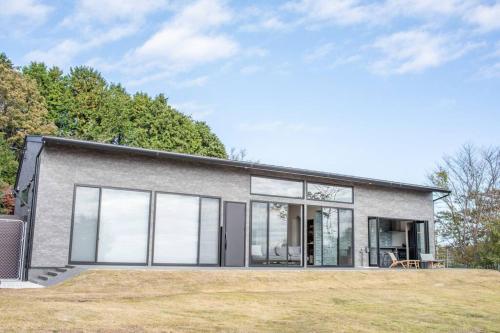 a gray house with glass doors and windows at Doggo伊豆　愛犬と過ごす最高の時間の為に造られた貸切宿。温泉、プライベートドッグランで最高の一時を。 in Ito