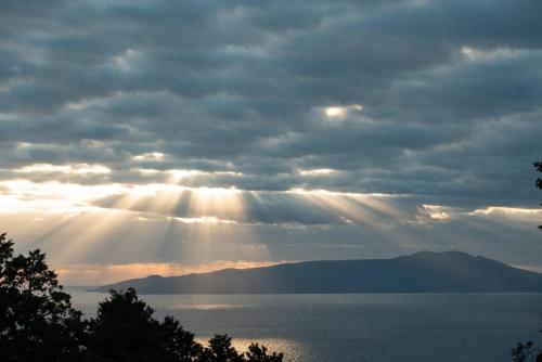 a cloudy sky with the sun shining on the water at Doggo伊豆　愛犬と過ごす最高の時間の為に造られた貸切宿。温泉、プライベートドッグランで最高の一時を。 in Ito