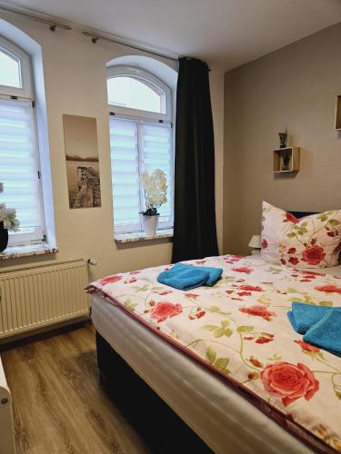 um quarto com uma cama com colcha floral e 2 janelas em Lehn dich zurück em Mühlhausen