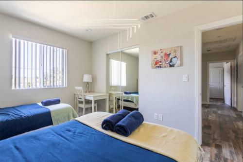 a bedroom with two beds with blue sheets and a desk at Cheerful 5BR house with parking near USC in Los Angeles