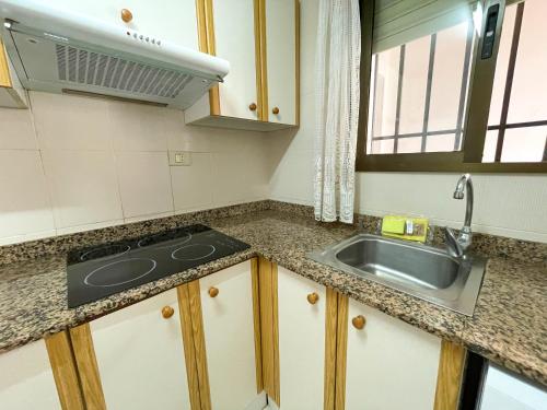 cocina con fregadero y fogones en Apartamentos Entreplayas 3000, en Oropesa del Mar