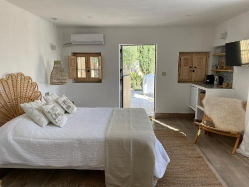 a bedroom with a white bed and a kitchen at Casa San Cayetano in Crevillente