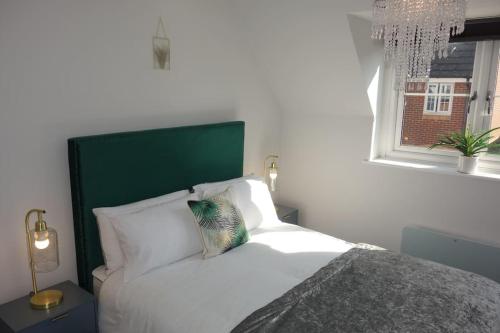 - une chambre avec un lit doté d'une tête de lit verte et d'une fenêtre dans l'établissement Tulip Place, à Chelmsford