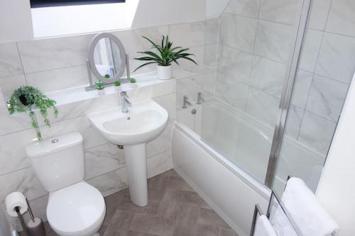 a white bathroom with a sink toilet and a bath tub at Tulip Place in Chelmsford
