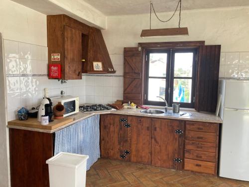 uma cozinha com armários de madeira e um frigorífico branco em Monte das Flores 