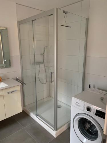 uma cabina de duche em vidro na casa de banho com uma máquina de lavar roupa em Harztor em Nordhausen