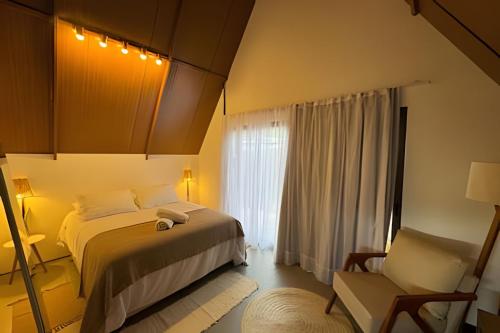 a bedroom with a bed and a chair and a window at Cabana Gameleira - Viagem Inspirada in Fernando de Noronha