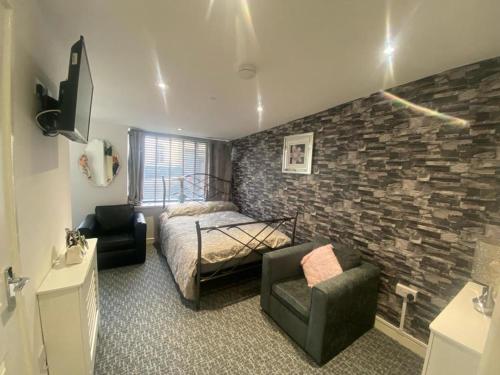 a bedroom with a brick wall with a bed and a chair at Beautiful 3-Bed apartment in Merthyr Tydfil in Merthyr Tydfil