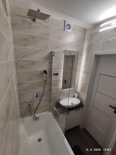 a bathroom with a bath tub and a sink at Apartmán M&K WEST in Poprad