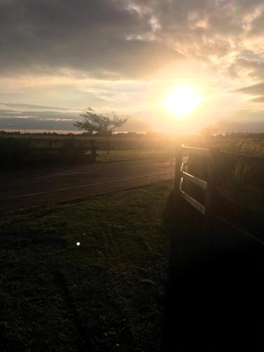 a sun setting over a field with a fence at Premium location - Sleeps 6 - Caravan on The Lakes in Mablethorpe