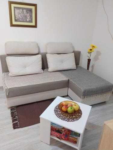 a living room with a couch with a bowl of fruit on a table at Apartman Plaza 9 in Veliko Gradište