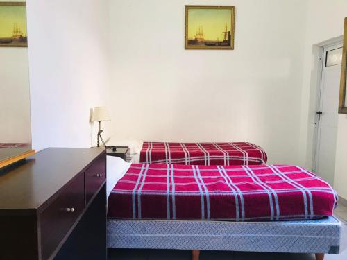 a bedroom with a bed and a dresser with a purple blanket at HOTEL PIAMONTE in Buenos Aires