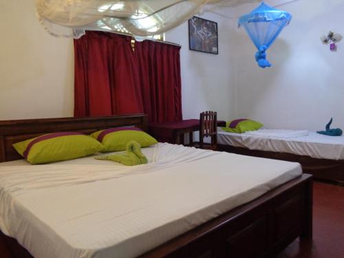 a bedroom with two beds with green pillows at Wellawaya Rest House in Wellawaya