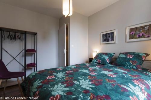 sypialnia z łóżkiem z zieloną narzutą kwiatową w obiekcie Le gîte de la poste w mieście Onlay