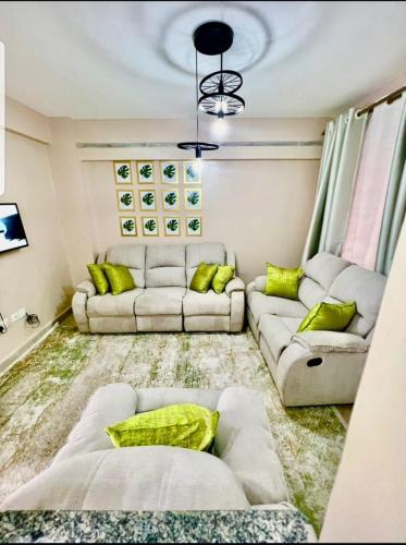 ein Wohnzimmer mit 2 Sofas und grünen Kissen in der Unterkunft Idaho apartment in Nakuru