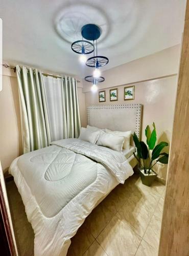 ein Schlafzimmer mit einem großen weißen Bett mit zwei blauen Lichtern in der Unterkunft Idaho apartment in Nakuru