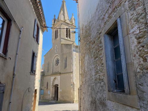 an old church with a clock tower in an alley at Le Gite de la Galerie Forge in Alaigne