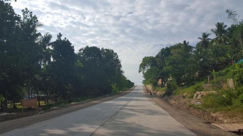 an empty road with trees on either side of it at La Vida Hostel Samal Island in Samal