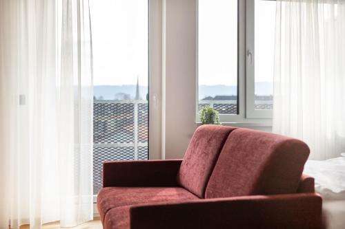 a living room with a red couch in front of a window at Brera Serviced Apartments Singen in Singen