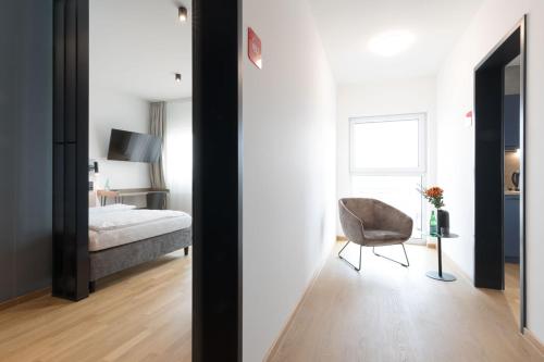 1 dormitorio con cama, silla y espejo en Brera Serviced Apartments Singen en Singen