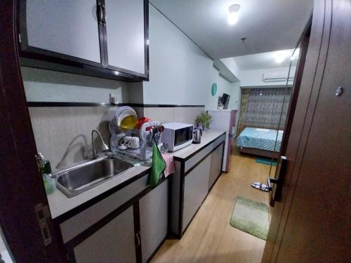 a small kitchen with a sink and a microwave at Sri Studio 07@Pollux Habibie Meisterstadt in Batam Center