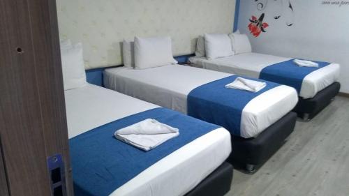 a room with three beds with blue and white sheets at Plaza Miranda in Bogotá