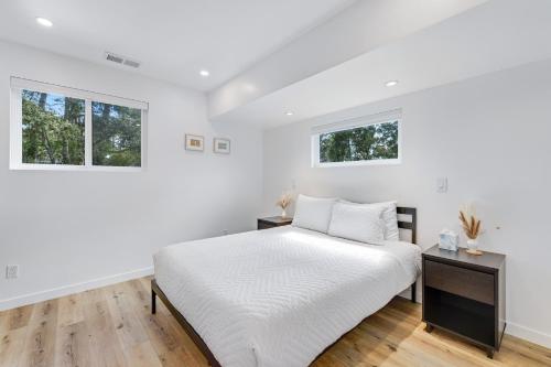 a white bedroom with a bed and two windows at Sunridge Point in Pebble Beach