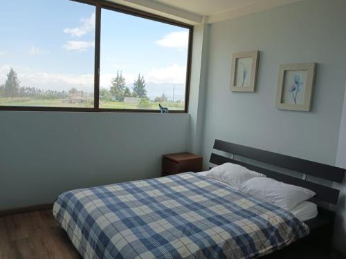 ein Schlafzimmer mit einem Bett und einem großen Fenster in der Unterkunft BellaVista Casa de Montaña in Latacunga
