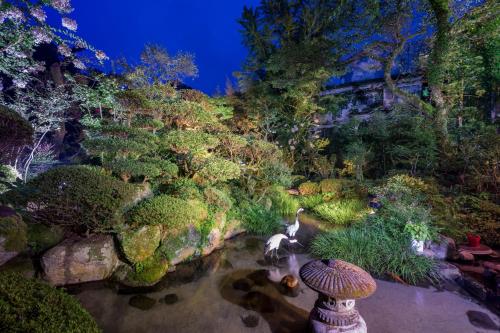 a garden at night with a pond and trees at Kakureisen in Saga