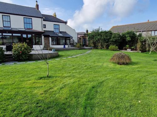 a house with a lawn with a small tree in the yard at The Cedars in Redruth