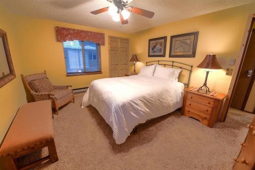 een slaapkamer met een bed, een stoel en een raam bij Trapper Condo Unit 3 in West Yellowstone